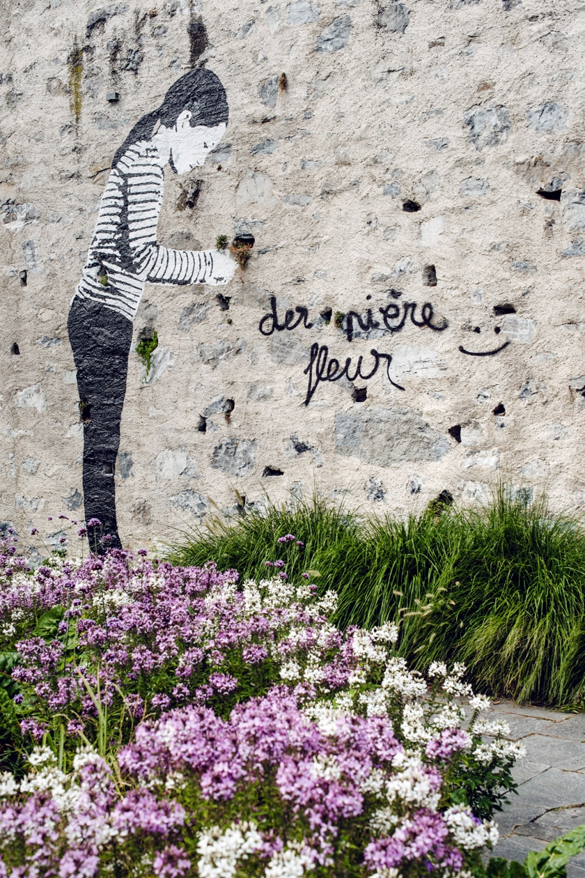 Lausanne Jardins 2019 – Place to Live – Un enfant peint sur les murs de Lausanne prend soin des plantes qui poussent de manière autonomes entre les pierres