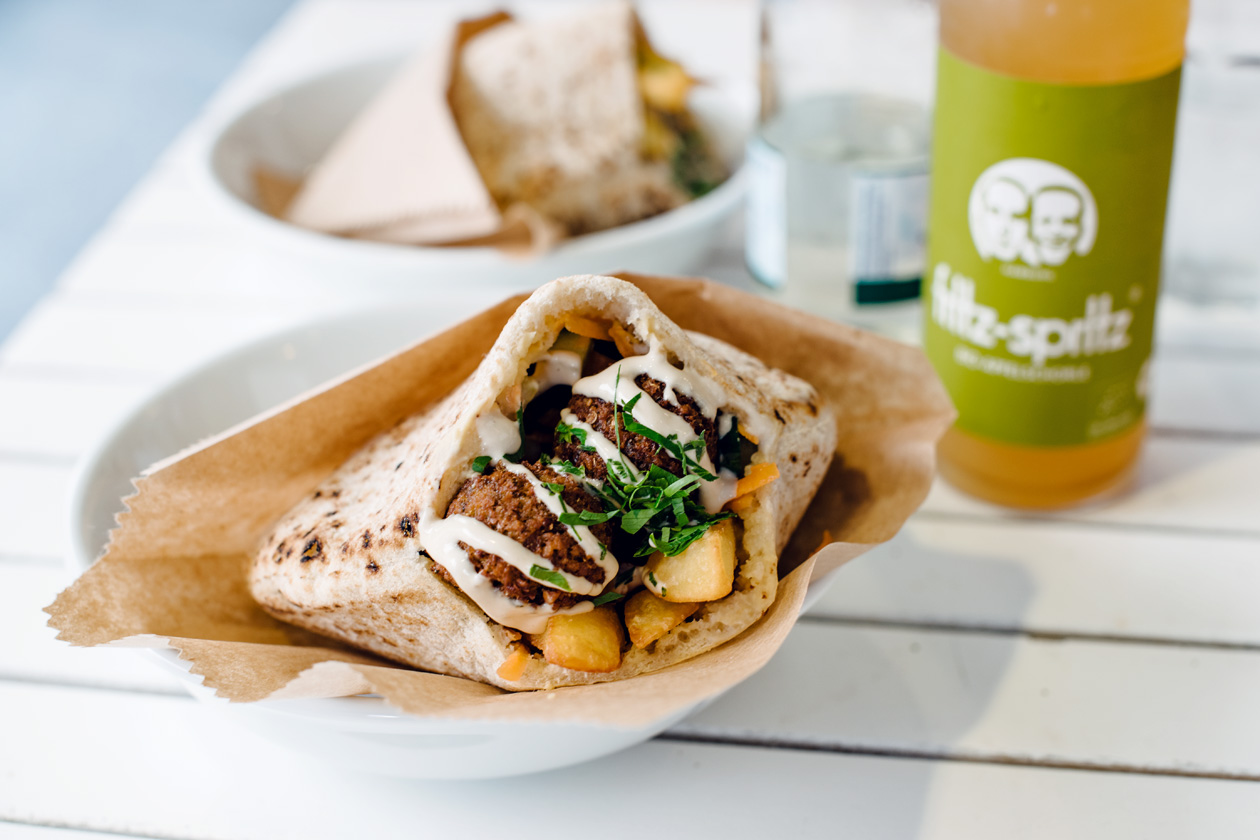 Pain pita garni de falafel, de hummus, de pommes de terre frites et de crudités chez Edo's Hummus Kuche à Freiburg im Breisgau