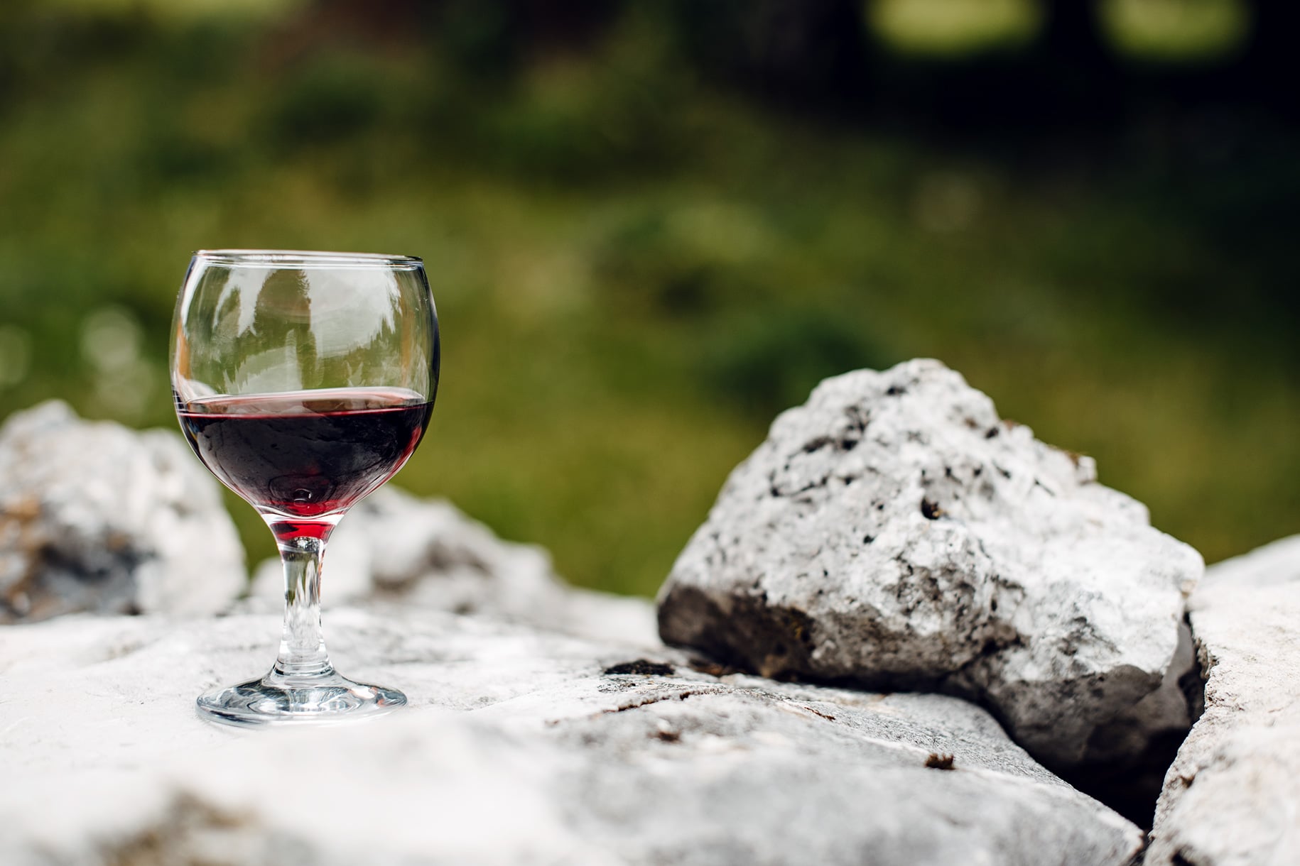 Verre de vin rouge posé sur un muret en pierres