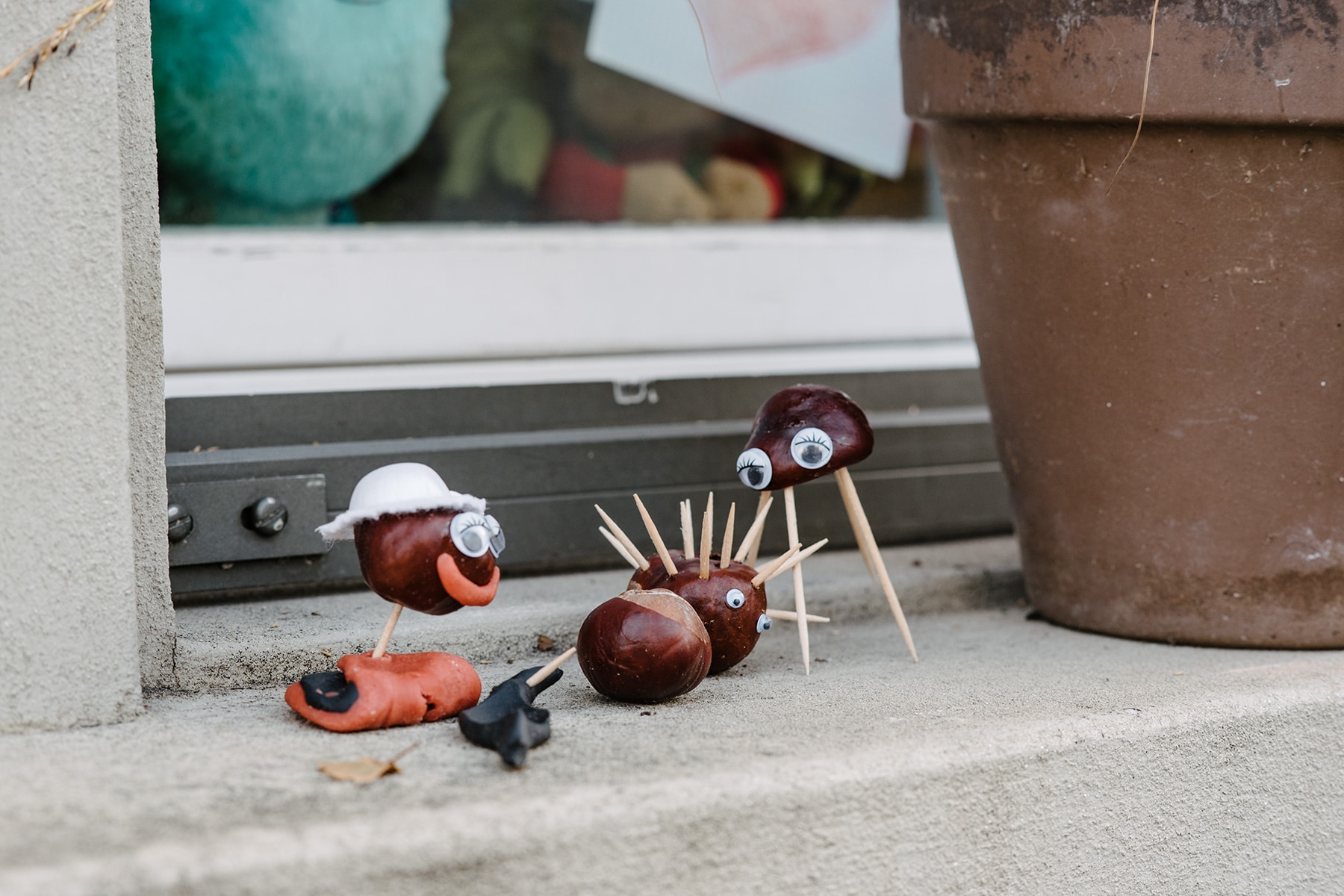 Petits personnages bricolés avec des marrons et de cure-dents, disposés sur le rebord d'une fenêtre